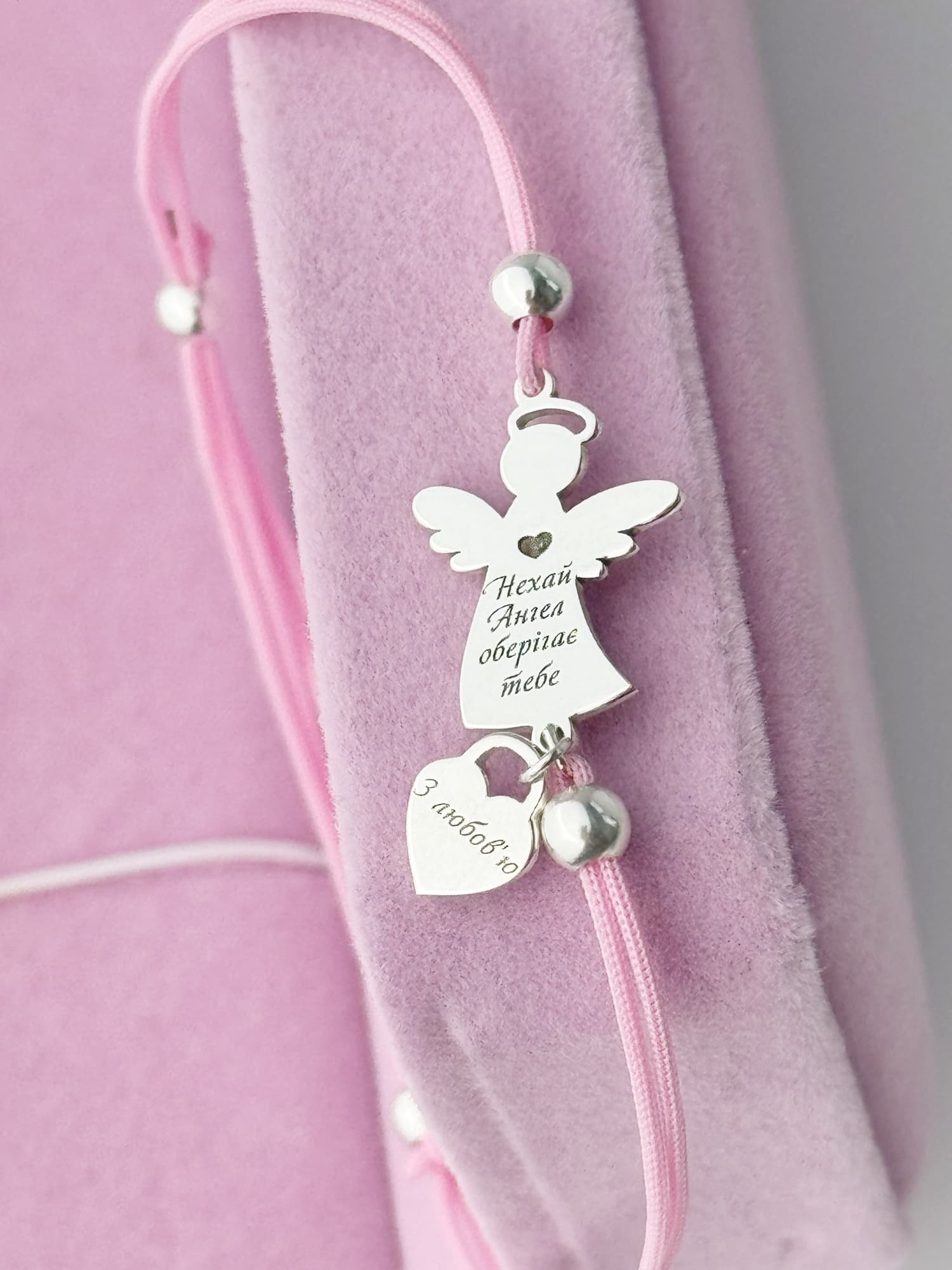 Silver angel bracelet with a heart on a pink cord