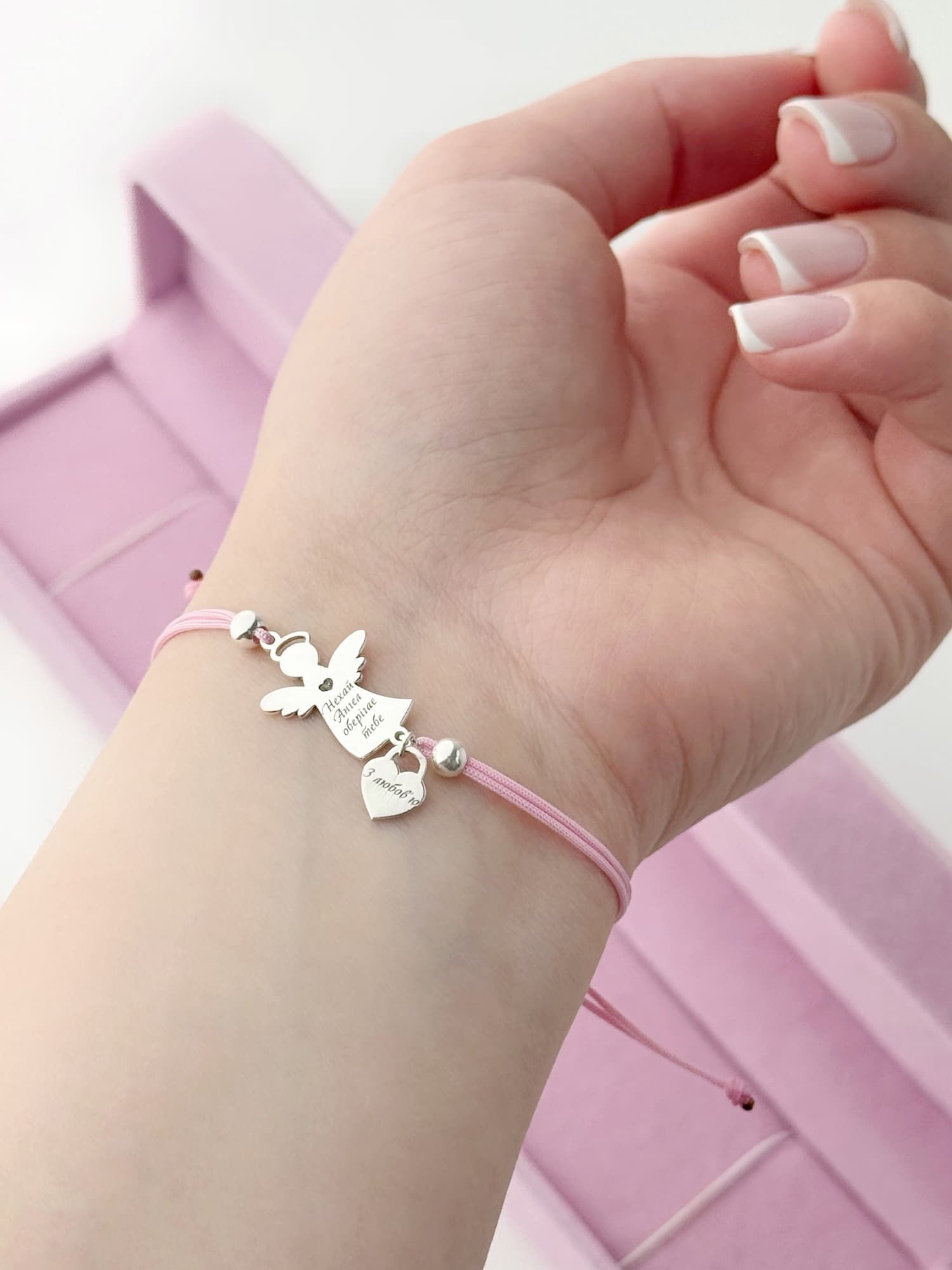 Silver angel bracelet with a heart on a pink cord