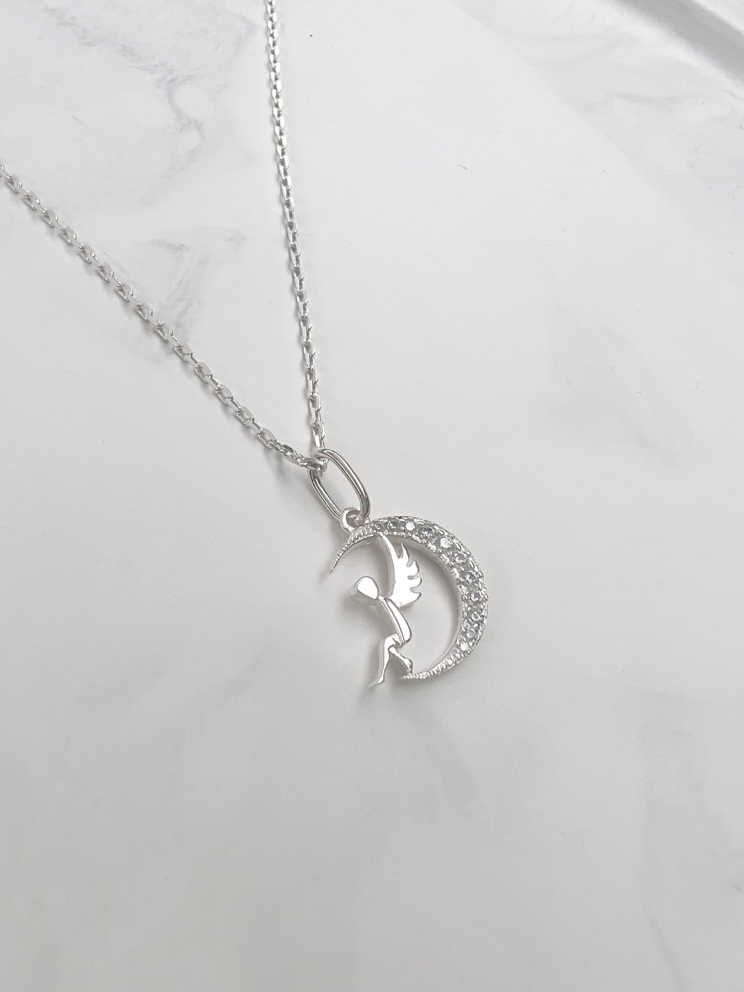Silver necklace with an angel-on-the-moon pendant and cubic zirconia