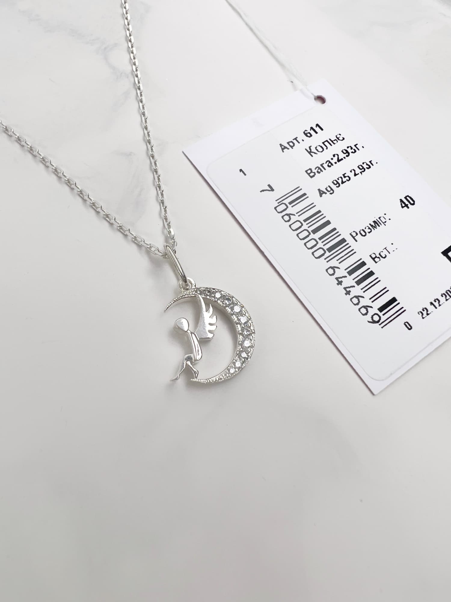Silver necklace with an angel-on-the-moon pendant and cubic zirconia