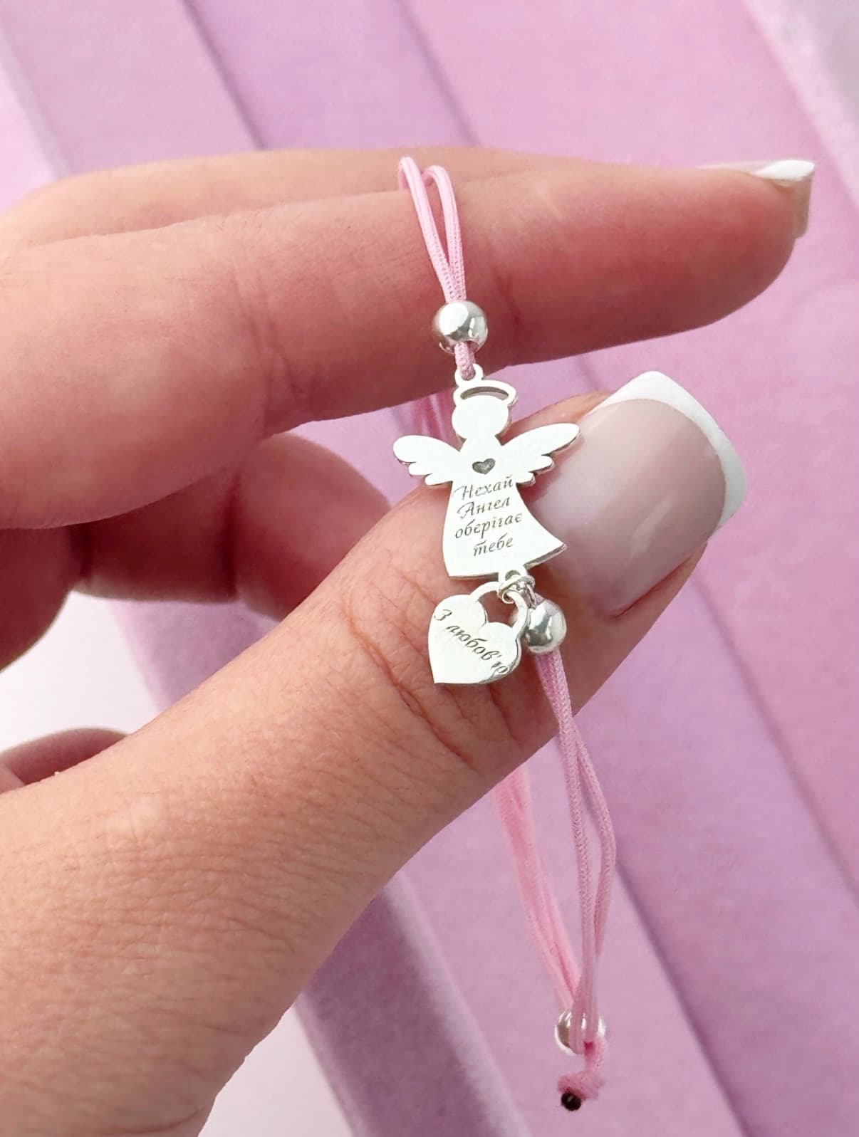 Silver angel bracelet with a heart on a pink cord